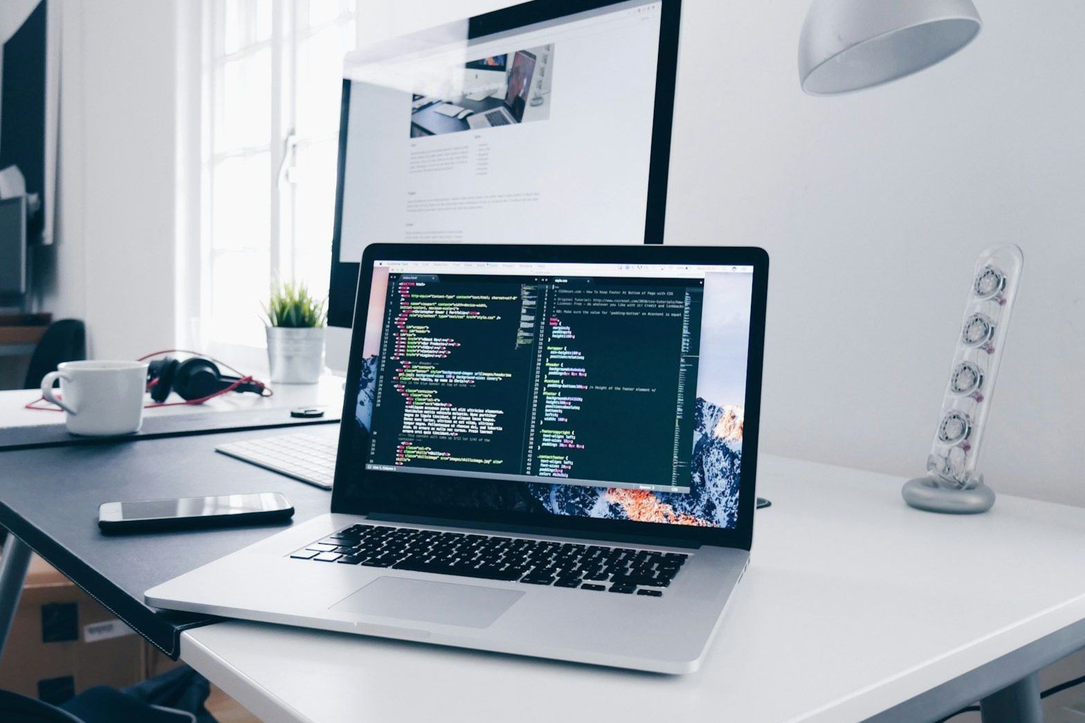 Laptop mit Quellcode auf einem aufgeräumten Entwicklerarbeitsplatz